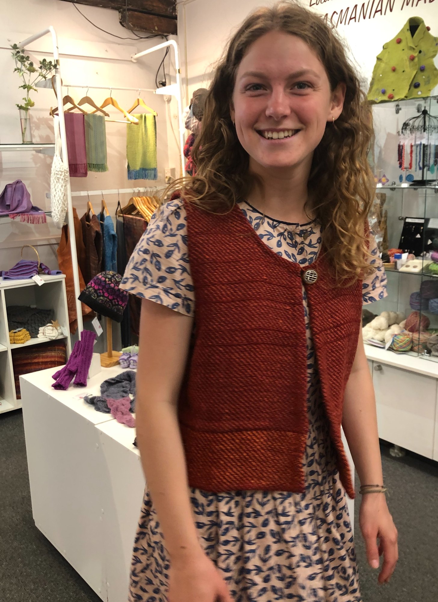 A cropped twill vest in rust and burnt orange, fastened with a single button.