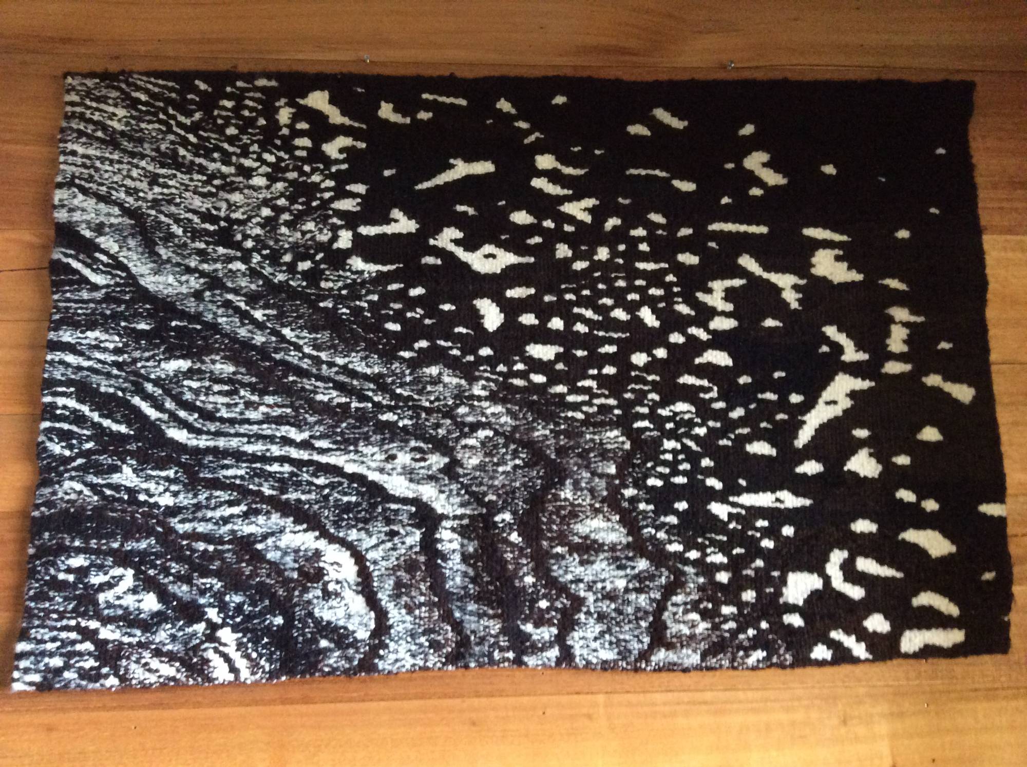 A black and white tapestry of water and rock, the light breaking into scattered flecks.