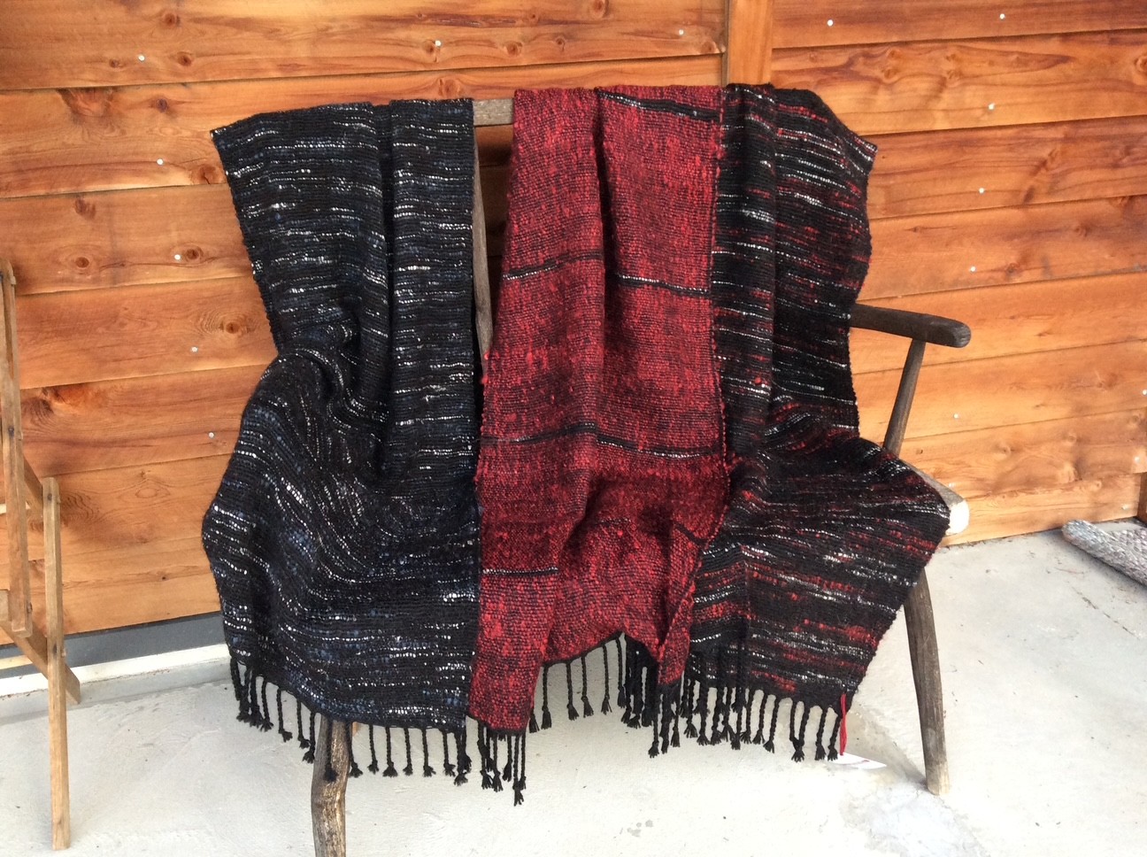 Textured throws in charcoal, deep red and silver-flecked black, with knotted fringes.